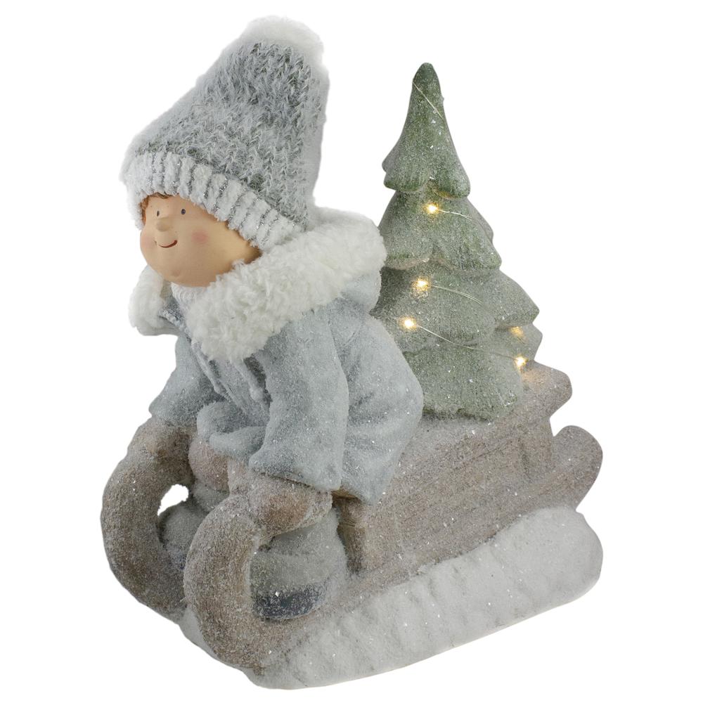 15" Beige and Green Lighted Boy on a Sled Christmas Decoration. Picture 1